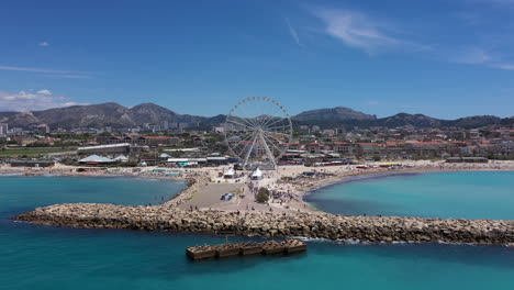 Aerial-back-traveling-over-Borely-beach-sunny-day-Marseille-big-wheel-attraction